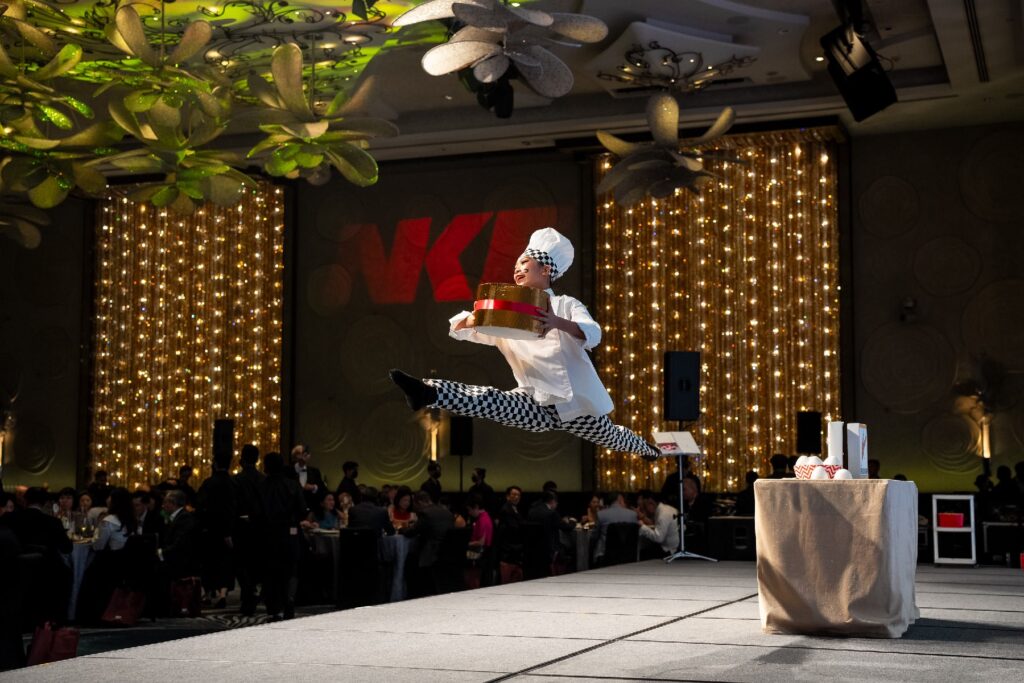 A graceful dancer mid-performance on stage, captured in a perfectly timed leap with dramatic lighting and expressive movement